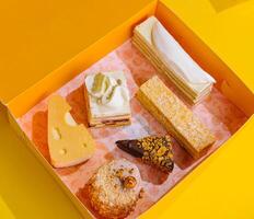 sortiert Kuchen Scheiben im Gelb Geschenk Box auf Gelb Hintergrund foto