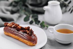 Eclair mit Schokolade Sahne und Haselnüsse und Tee foto