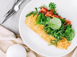 Omelett mit Rucola, Tomaten und Basilikum im ein Teller foto