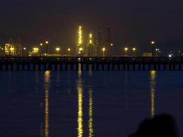 Nacht Beleuchtung auf Container Schiff Hafen sehen über Wasser foto