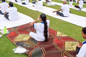 Neu Delhi, Indien, Juni 21, 2023 - - Gruppe Yoga Übung Session zum Menschen beim Yamuna Sport Komplex im Delhi auf International Yoga Tag, groß Gruppe von Erwachsene Teilnahme Yoga Klasse im Kricket Stadion foto