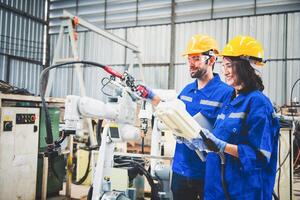 Mechaniker des Ingenieurteams, der den Roboterarm der Computersteuerung zum Schweißen von Stahl in der Werkstatt der Stahlfabrik verwendet. Programmiersoftware für Industrieroboter für die automatisierte Fertigungstechnik foto