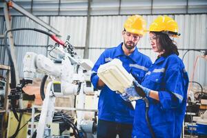 Mechaniker des Ingenieurteams, der den Roboterarm der Computersteuerung zum Schweißen von Stahl in der Werkstatt der Stahlfabrik verwendet. Programmiersoftware für Industrieroboter für die automatisierte Fertigungstechnik foto