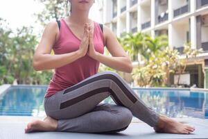 schlank Frau üben Yoga in der Nähe von Schwimmen Schwimmbad beim Eigentumswohnung. asiatisch Frau tun Übungen im Morgen. Gleichgewicht, Meditation, Entspannung, ruhig, gut Gesundheit, Glücklich, entspannen, gesund Lebensstil Konzept foto