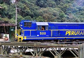 aguas Calientes, Peru, 2015 - - Eisenbahn Blau und Gelb Motor ziehen um durch Stadt, Dorf foto