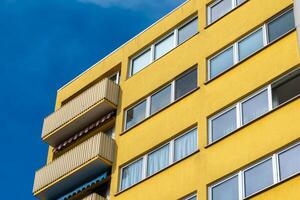 ein Gelb Gebäude mit ein Balkon und viele Fenster foto