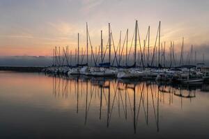 Segelboote reflektiert im ein neblig Rosa Sonnenaufgang auf Ruhe Wasser foto