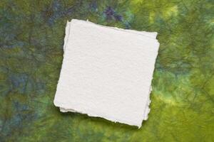 klein Platz Blatt von leer Weiß khadi Papier gegen bunt marmoriert Papier foto