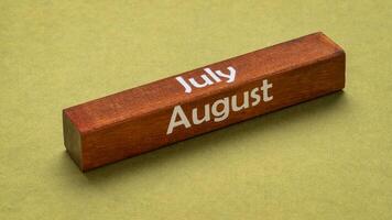 Juli und August Text auf hölzern Block gegen handgemacht Grün Papier, Kalender Konzept foto