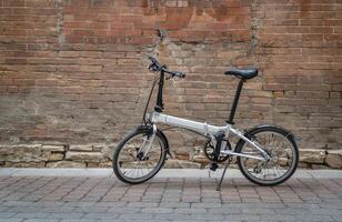 Leicht falten Fahrrad im ein Gasse gegen Grunge Backstein Mauer foto