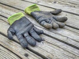 ein Paar von Gut gebraucht, schmutzig Bambus Garten Handschuhe auf ein hölzern rustikal Deck foto