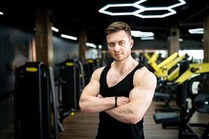 sportlich jung männlich Modell- mit stark Hände. gut aussehend stark Mann posieren beim das Fitnessstudio. foto