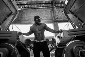 schwarz und Weiß Bild von muskulös Mann. gut aussehend stark Bodybuilder draussen suchen zu seine Seite. foto