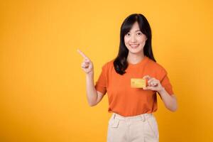 zuversichtlich asiatisch weiblich Käufer mit ihr Anerkennung Karte und Smartphone zu machen sichern online Transaktionen auf ein beschwingt Gelb Hintergrund. foto