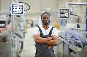Porträt von afrikanisch amerikanisch männlich Ingenieur im Uniform und Stehen im industriell Fabrik foto