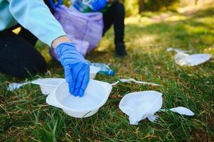 Hand setzt Plastik Trümmer im das Müll Tasche im das Park foto