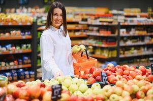 Frau im ein Supermarkt beim das Gemüse Regal Einkaufen zum Lebensmittel, sie ist wählen foto