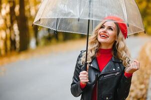 Frau mit Regenschirm Gehen beim das Regen im schön Herbst Park. foto