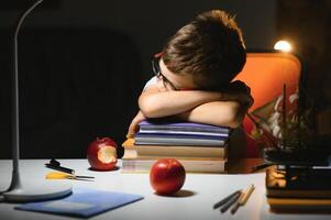 jung Teenager Schüler beim das Tabelle tun Hausaufgaben im das dunkel Zimmer foto