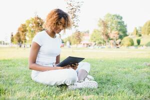 Außenporträt eines lächelnden schwarzen Mädchens des Teenagers unter Verwendung einer taktilen Tafel - afrikanische Leute foto