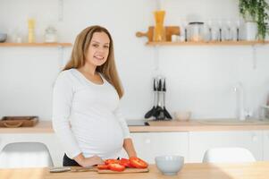 schwanger Frau im Küche Herstellung Salat foto