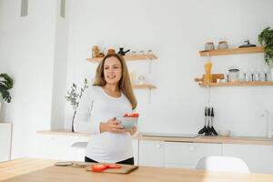 schwanger Frau im Küche Herstellung Salat foto