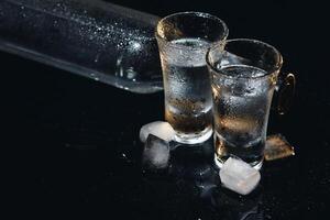 Nahansicht Aussicht von Flasche und Brille von Wodka Stehen isoliert auf schwarz. foto