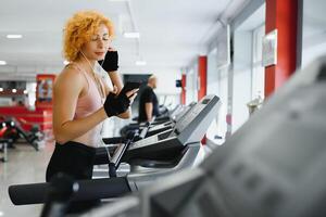 attraktiv jung Frau läuft auf ein Laufband, ist beschäftigt, verlobt im Fitness Sport Verein foto