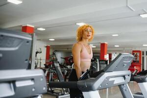 attraktiv jung Frau läuft auf ein Laufband, ist beschäftigt, verlobt im Fitness Sport Verein foto