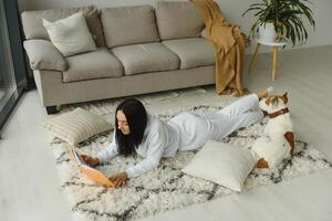 Mädchen lesen ein Buch mit ihr Hund neben ihr. Frau liest ein Buch mit Hund auf das Fußboden foto