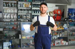 Porträt von ein gut aussehend Verkäufer im ein Auto Teile speichern. das Konzept von Auto Reparatur foto