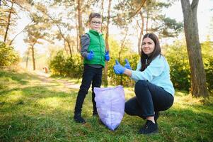 Frau Freiwillige und wenig Junge pflücken oben das Plastik Müll foto