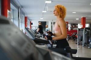 attraktiv jung Frau läuft auf ein Laufband, ist beschäftigt, verlobt im Fitness Sport Verein foto