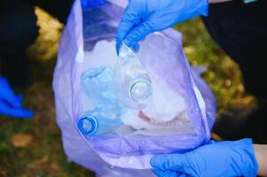 Hand setzt Plastik Trümmer im das Müll Tasche im das Park foto