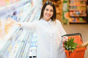 schöne junge Frau, die für Getreide, Masse in einem Lebensmittelsupermarkt einkauft foto