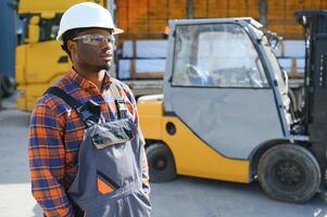 afrikanisch amerikanisch Mann beim arbeiten. Fachmann Betrieb Maschinenbau. jung Arbeiter Gabelstapler Treiber foto