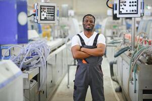 afrikanisch männlich Ingenieur. Steuerung ein Material Produktion Maschine System, Arbeiten im ein Plastik und Stahl Industrie hinsichtlich das Firma Produkt Geschäft. foto