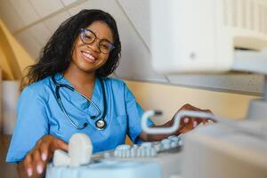 lächelnd afrikanisch Frau Arzt mit Ultraschall Scanner im Hand, Arbeiten auf modern Ultraschall Scannen Maschine im Licht Zimmer im Klinik. Porträt von 4d Ultraschall Scannen Maschine Operator foto