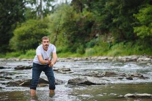 bärtig Mann fangen Fisch. Sommer- Freizeit. reifen Mann Angeln auf das Teich. Porträt von heiter Senior Mann Angeln. männlich Angeln. Fischmann gehäkelt rotieren in das Fluss warten groß Fisch foto