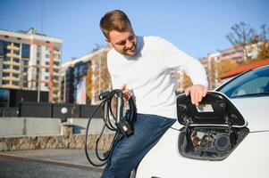 Mann Gebühren ein elektrisch Auto beim das Laden Bahnhof foto