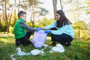 Frau Freiwillige und wenig Junge pflücken oben das Plastik Müll foto