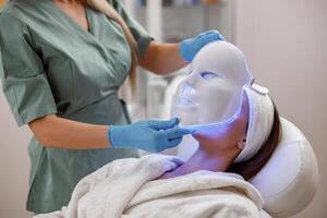 kosmetisch Verfahren mit LED Gesichts- Maske zum weiblich Gesicht. Photon Therapie foto