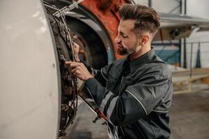 männlich Luftfahrt Mechaniker reparieren Flugzeug im Halle foto