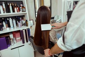 Friseur Bürsten lange und glatt braun Haar von weiblich Klient beim Schönheit Salon foto