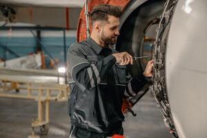 männlich Luftfahrt Mechaniker reparieren Flugzeug im Halle foto