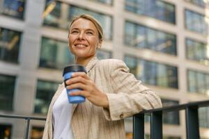 Geschäft Frau gehen zu Arbeit während Trinken Kaffee auf Büro Gebäude Hintergrund. hoch Qualität Foto