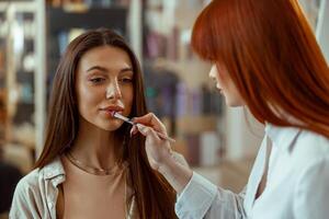 weiblich Klient bekommen bilden von Fachmann bilden Künstler bewirbt sich Lipgloss auf ihr Lippen foto