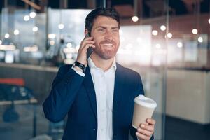 gut aussehend Geschäftsmann mit nehmen Weg Kaffee Tasse reden auf Handy mit Geschäft Partner foto