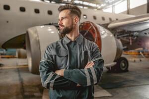 bärtig Mann Fluggesellschaft Mechaniker Stehen in der Nähe von Flugzeug im Halle foto