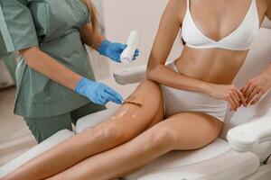 Besondere Salbe angewendet auf Klient Beine Vor Laser- Epilation Verfahren im Schönheit Salon foto